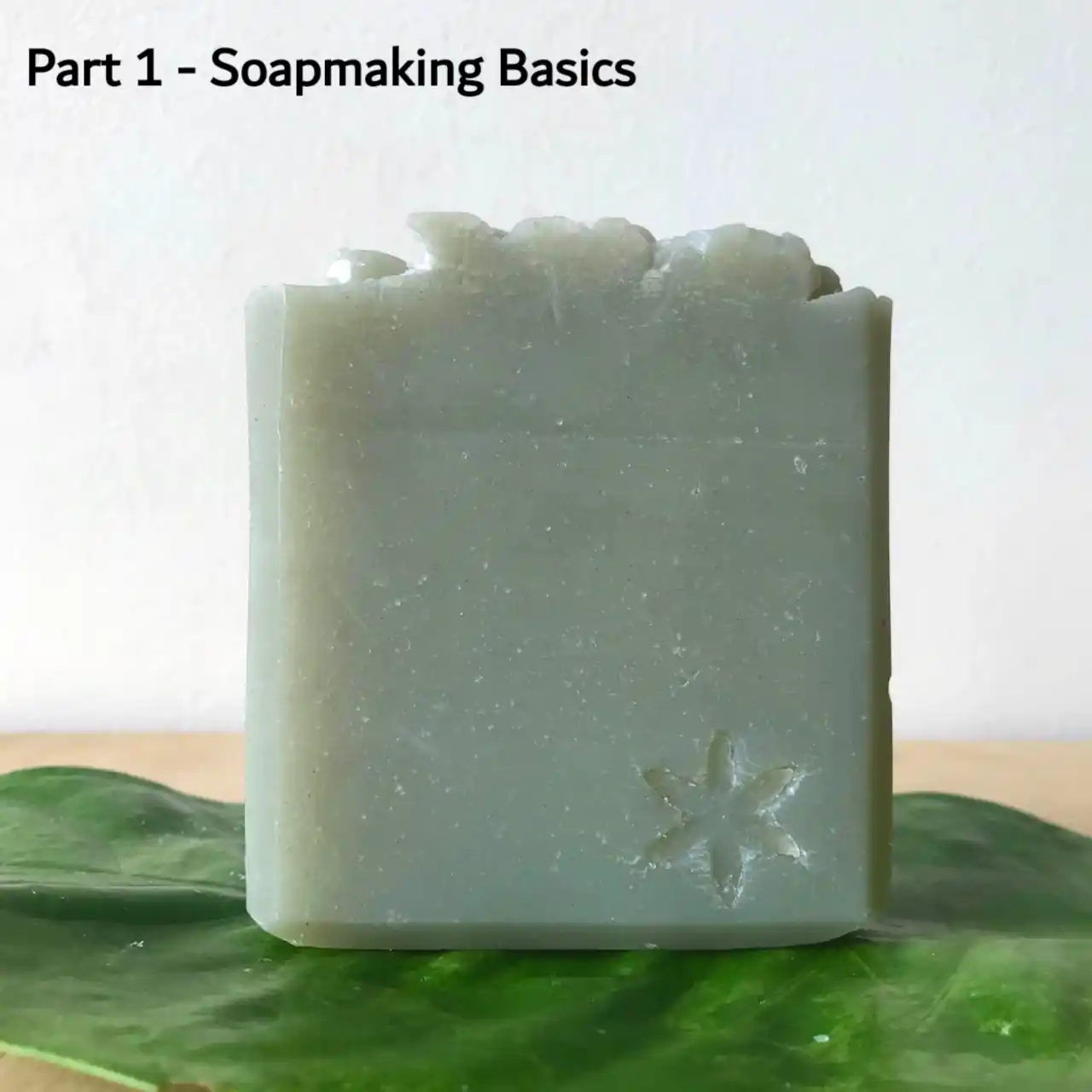 a green bar of soap with writing: part 1-soapmaking basics