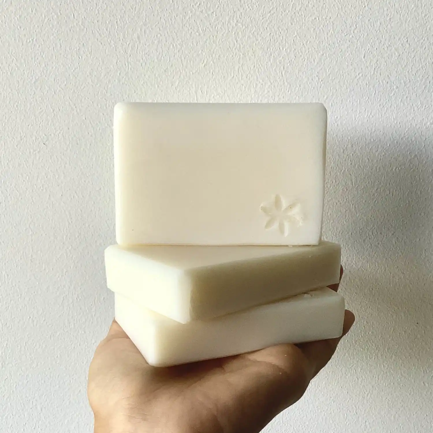 hand holding three bars of white soaps